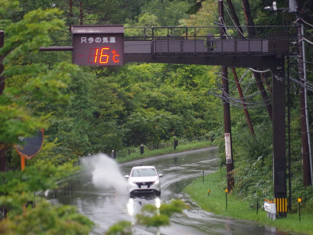 強い雨の中を走る車と水しぶき